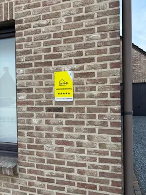 a yellow sign on the side of a brick wall at Villa Luna in Oudsbergen