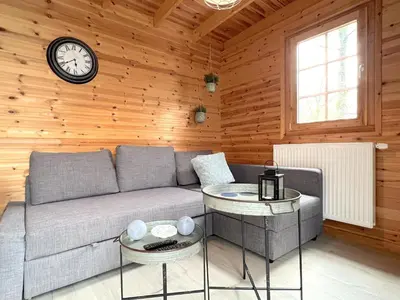 a living room with a couch and a clock on the wall at Chalet Wielsmer in Zutendaal