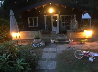 a house with an umbrella and a bike in front of it at Vakantie Bos Huisje “Meibloempje” in Lanaken