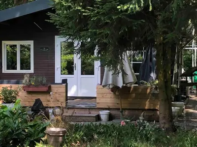 a front porch of a house with a white door at Vakantie Bos Huisje “Meibloempje” in Lanaken