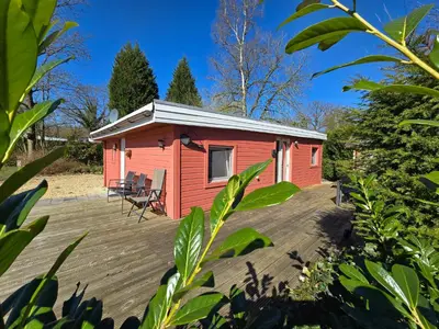a red tiny house on a wooden deck at Cozychalet met prive Hot tub in Lanaken