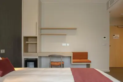 a bedroom with a bed and a desk at Hôtel Les Fines Gueules in Herve