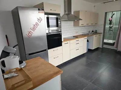 a kitchen with a stainless steel refrigerator and white cabinets at appartement ouvert sur une pièce in Liège