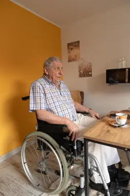an older man in a wheelchair sitting at a table at Alivio - Thuiskomen bij jezelf op vakantie in Lummen