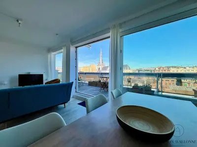 a living room with a table and a large window at Le Panoramique des Carmes - Vue Cathédrale in Liège