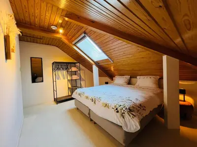 a bedroom with a large bed with a wooden ceiling at Vakantievilla 't Boshuys in Lommel