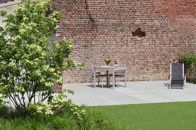 a table with flowers on it next to a brick wall at Maas & Me in Dilsen-Stokkem