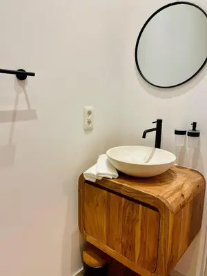 a bathroom with a sink and a mirror on a wooden table at Chaleureux petit appartement in Liège