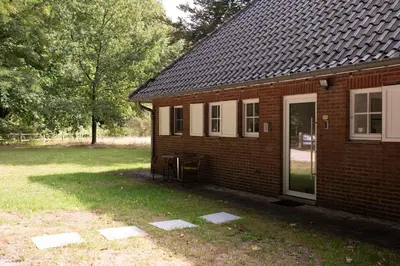 a small brick house with a door and a yard at Tussen Heide en Bos in het Nationaal Park Hoge Kempen in Oudsbergen