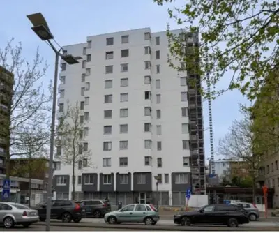 a tall white building with cars parked in front of it at Skylodgenk in Genk