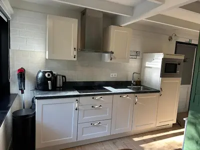 a kitchen with white cabinets and a sink and a refrigerator at Vakantiehuis Lanaken in Lanaken