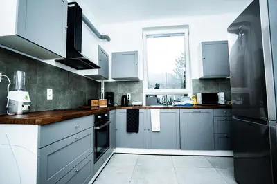 a kitchen with blue and white cabinets and a window at Chambre R0 avec salle de bain partagée près de l'hôpital de la Citadelle à Liège in Liège