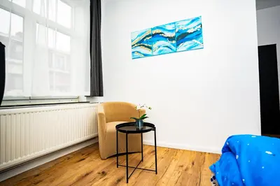 a living room with a table and a chair at Chambre R1 avec salle de bain privée in Liège