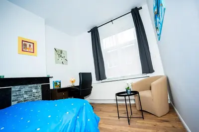 a bedroom with a bed and a chair and a window at Chambre R1 avec salle de bain privée in Liège