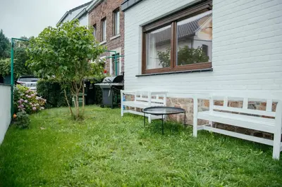 two benches sitting in the grass next to a window at La Courte Échelle in Verviers