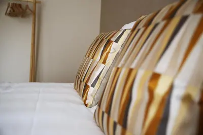 a bed with a striped pillow on top of it at Le 118 Guillemins, avec Parking in Liège