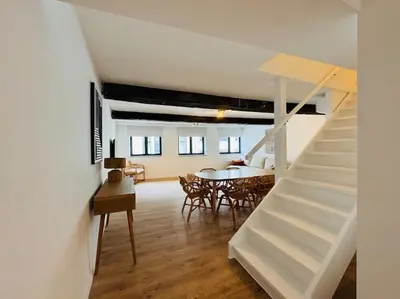 a living room with a staircase and a table and chairs at Urbanchic Appartement Evasion 3D in Liège