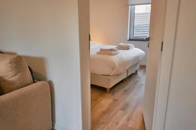 a bedroom with a bed and a chair and a window at Urbanchic Appartement Chill 3B in Liège