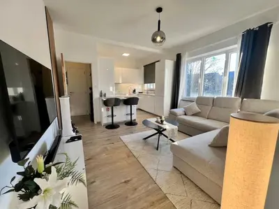 a living room with a couch and a kitchen at Modern Business Flat - Courts et moyens séjours in Liège