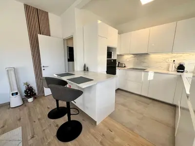 a kitchen with white cabinets and a bar with a stool at Modern Business Flat - Courts et moyens séjours in Liège