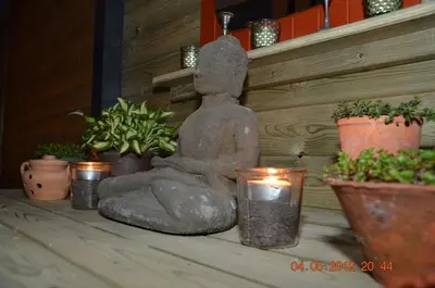 a statue sitting on a table with plants and candles at B&B Noord-Zuid in Zonhoven