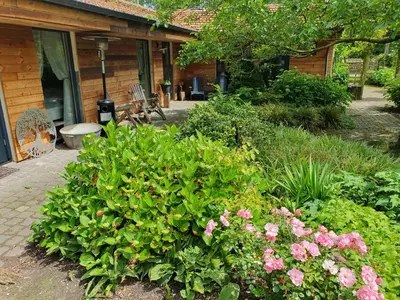 a garden with pink flowers in front of a building at B&B Land of Tir Nan Og in Lommel