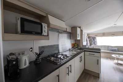 a small kitchen with a stove and a microwave at Vakantiehuis 25 min Roermond Maasmechelen Maastricht in Kinrooi