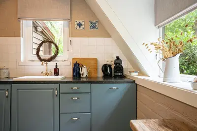 a kitchen with blue cabinets and a sink and a window at Boshuisje Rekem - Fleur in Lanaken