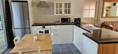 a kitchen with white cabinets and a wooden table at Vakantiehuis Pippa in Peer