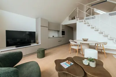a living room with a table and a staircase at Chalet Eau Vive Mase in Maaseik