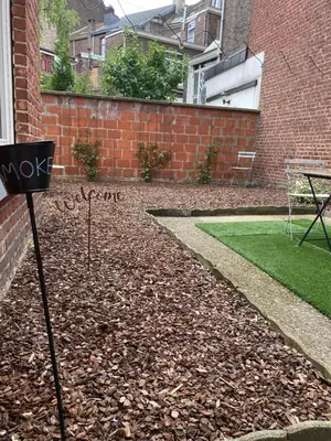 a garden with a lawn and a brick wall at Sweet Home in Liège