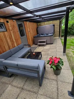 a patio with a couch and a hot tub at Tiny Lodge met prive Jacuzzi in Lanaken