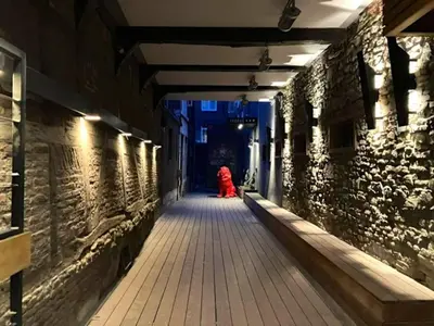 a woman in a red dress walking down an alley at La Nano Maison de Liège in Liège