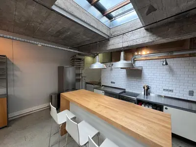a kitchen with a wooden counter and white chairs at Sleep You Soon - Loft & parking in Liège