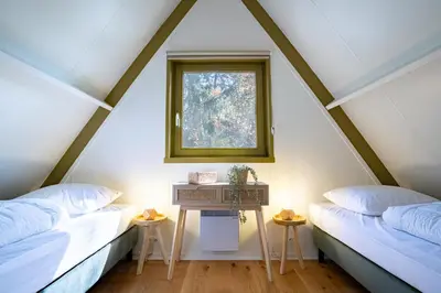 two beds in a attic room with a window at Boshuisje Rekem - Olive in Lanaken