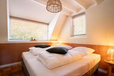 a bed with pillows on it in a room with windows at Boshuisje Rekem - Olive in Lanaken