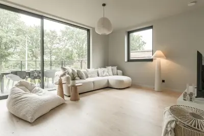 a living room with a white couch and a large window at Vakantie aan de Maas - Vakantiewoning Neerhof in Kinrooi