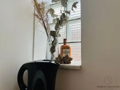 a bottle of whiskey sitting on a window sill with flowers at Le Wallon - Cointe Guillemins Botanique in Liège