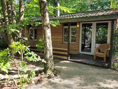 a wooden cabin with a chair on the porch at Corgi-Flowerhuisje in Lanaken