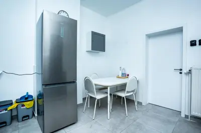a kitchen with a refrigerator and a table with chairs at Chambre R2 avec salle de bain partagée près de l'hôpital de la Citadelle à Liège in Liège