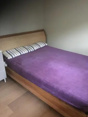 a bed with a purple blanket on top of it at Daisy home in Diepenbeek