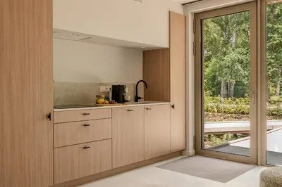 a kitchen with wooden cabinets and a large window at Suite - 2 personen - Woodz Lodges in Heusden - Zolder