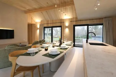 a kitchen and living room with a large white table at Villa Lodge met Jacuzzi - 8 personen - Woodz Lodges in Heusden - Zolder