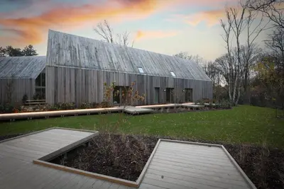 a large wooden barn with a lawn in front of it at Lodge - 8 personen - Woodz Lodges in Heusden - Zolder
