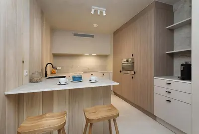 a kitchen with wooden cabinets and a counter with two stools at Groepslodge - 10 personen - Woodz Lodges in Heusden - Zolder