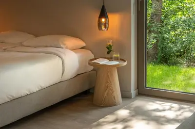 a bedroom with a bed with a table and a window at Groepslodge - 10 personen - Woodz Lodges in Heusden - Zolder