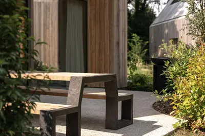 a wooden bench sitting in front of a building at Groepslodge - 10 personen - Woodz Lodges in Heusden - Zolder