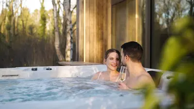 a man and woman in a hot tub with a glass at Lodge met Jacuzzi - 6 personen - Woodz Lodges in Heusden - Zolder