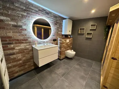 a bathroom with a white sink and a brick wall at Au 171 Le loft avec un sauna in Flémalle-Grande