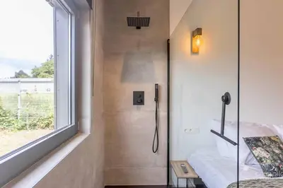 a bathroom with a shower with a window and a bed at Lodge 4 you gite de luxe pour 4 personnes in Verviers